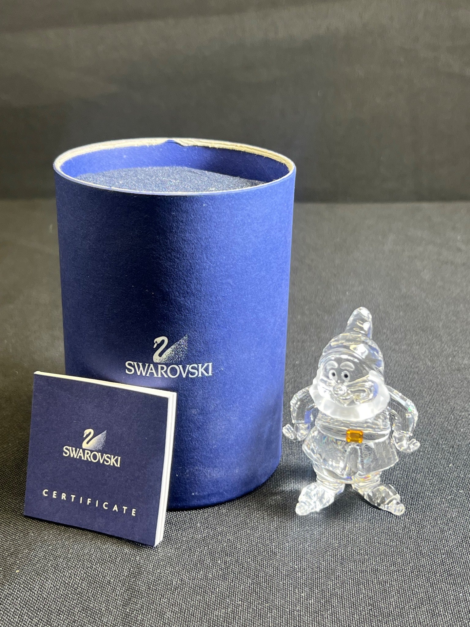 Crystal figure next to a Swarovski branded box and certificate on a gray surface