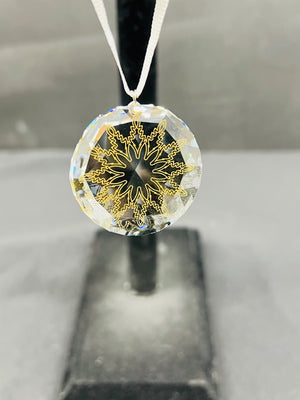 Crystal pendant with gold snowflake design on a gray background