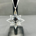 Clear star-shaped pendant on a black stand with a gray background