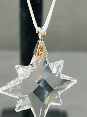Clear star-shaped pendant on a chain against a neutral background