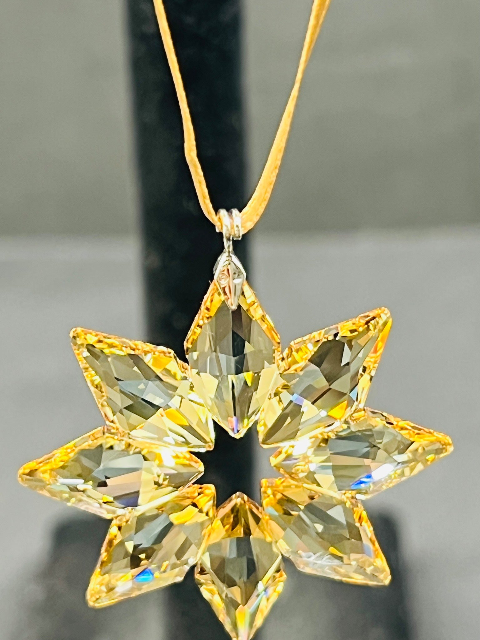 Star-shaped crystal pendant on a gold chain against a neutral background