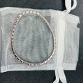 Bracelet with clear stones on a sheer white bag against a dark background