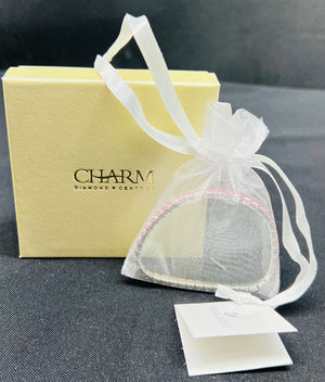 Heart-shaped jewelry box with a white ribbon and 'Charm' branding on a dark surface.