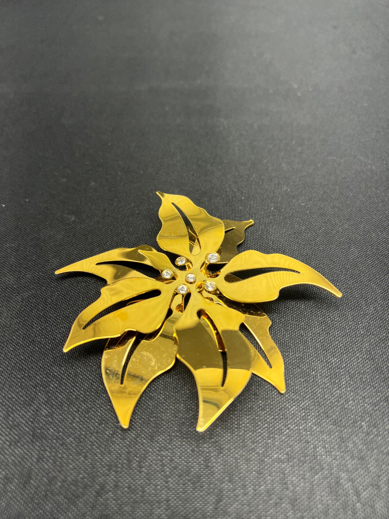 Gold leaf-shaped brooch on a dark gray background