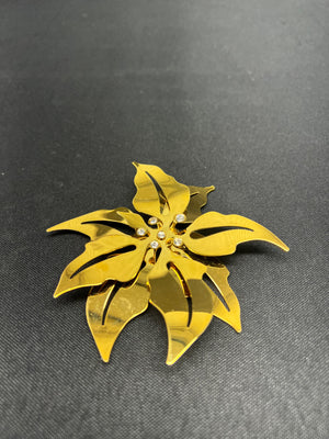 Gold leaf-shaped brooch on a dark gray background