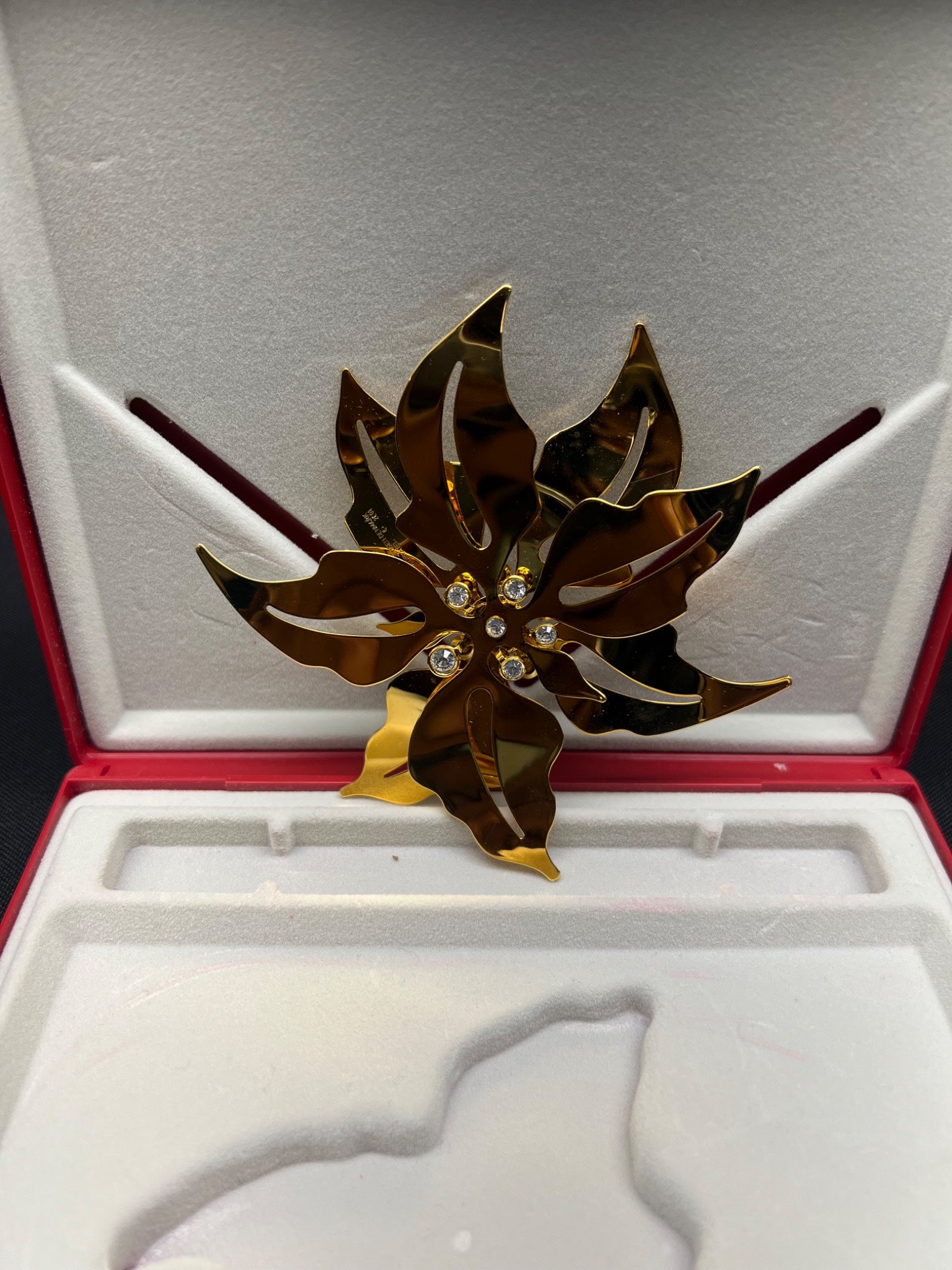 Gold and brown decorative item in a red and white box