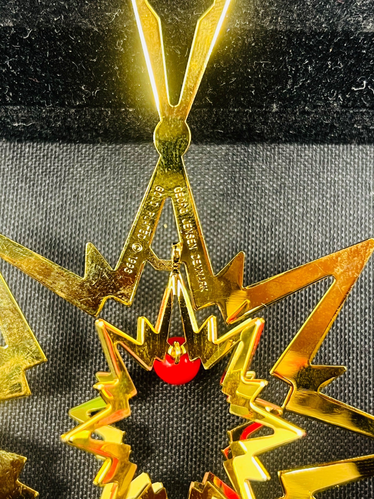 Gold metal star-shaped object with red center on a textured black surface