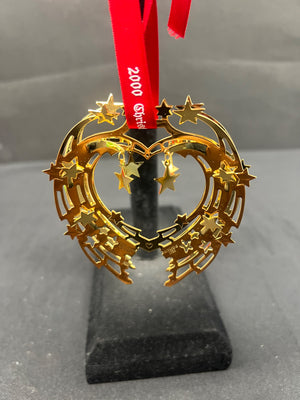 Gold star-shaped ornament on a stand with a red ribbon against a gray background