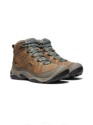 Pair of brown hiking boots with blue laces on a white background