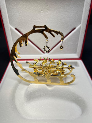 Gold and black decorative item with star design on a white cushioned surface