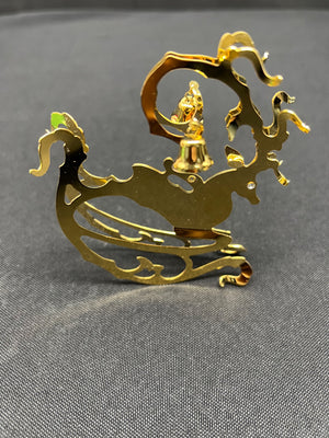 Gold dragon-shaped object with a figure on top against a gray background