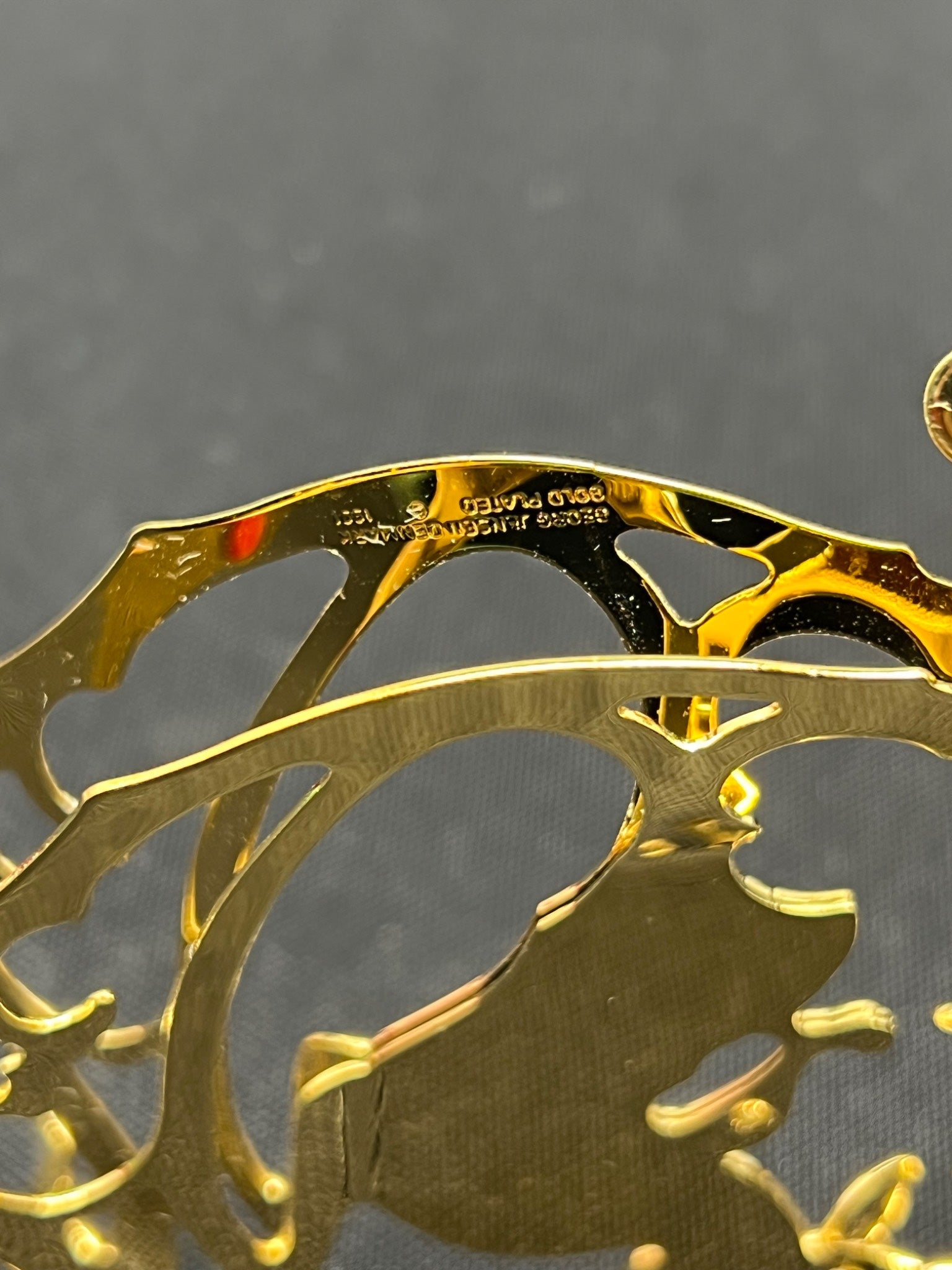 Gold metal object with engraved design on a gray background