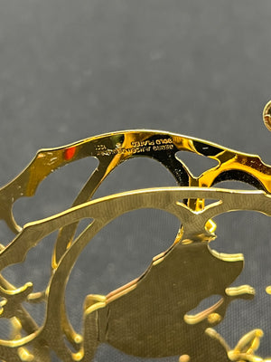 Gold metal object with engraved design on a gray background