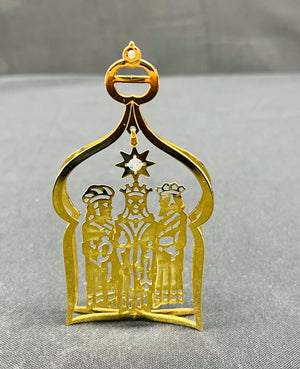 Gold ornament with three figures and a star on a gray background