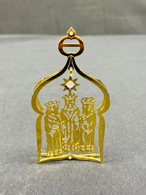 Gold decorative item with three figures and a star on a gray background