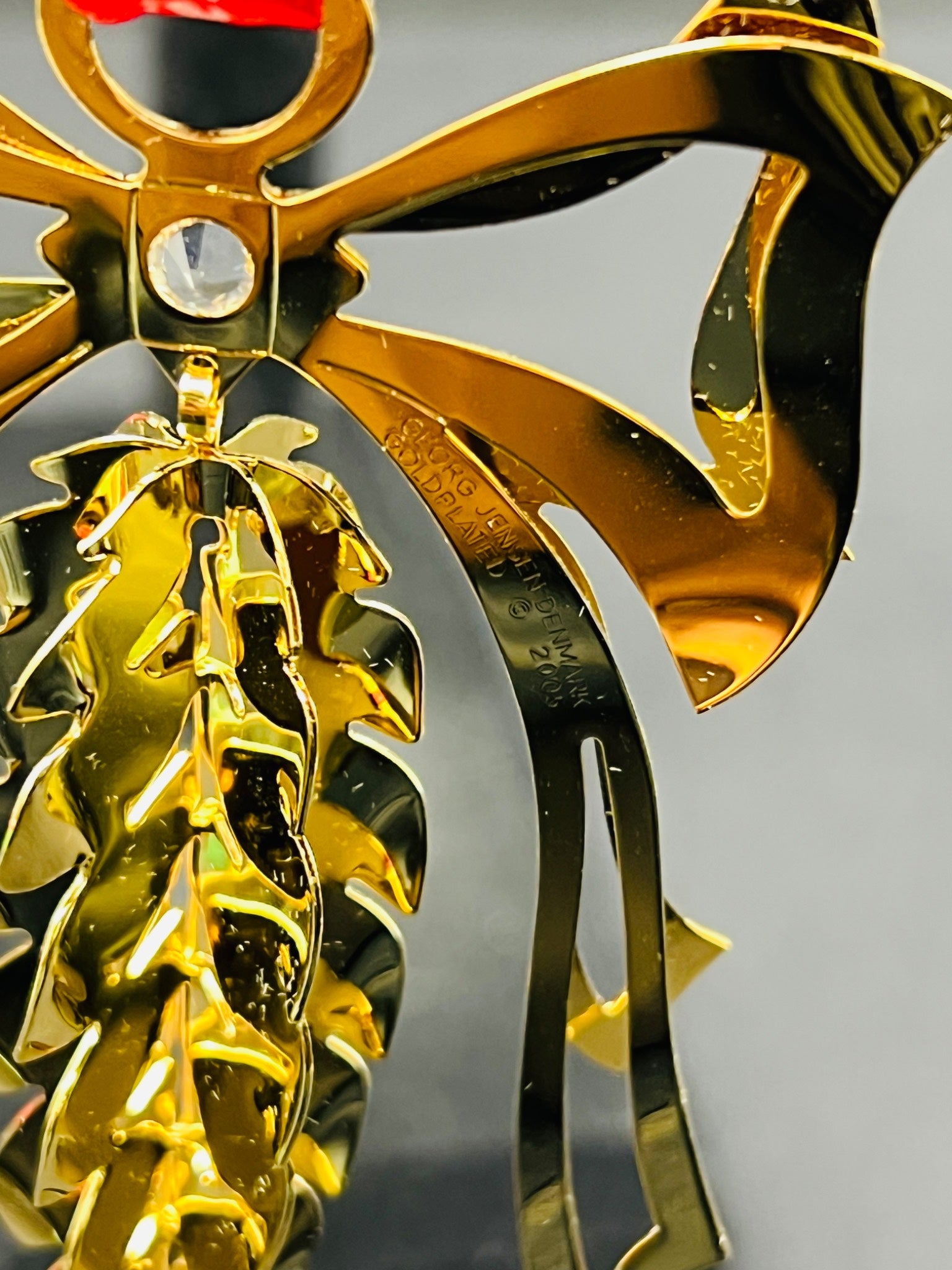 Gold scorpion figurine with red eyes on a gray background