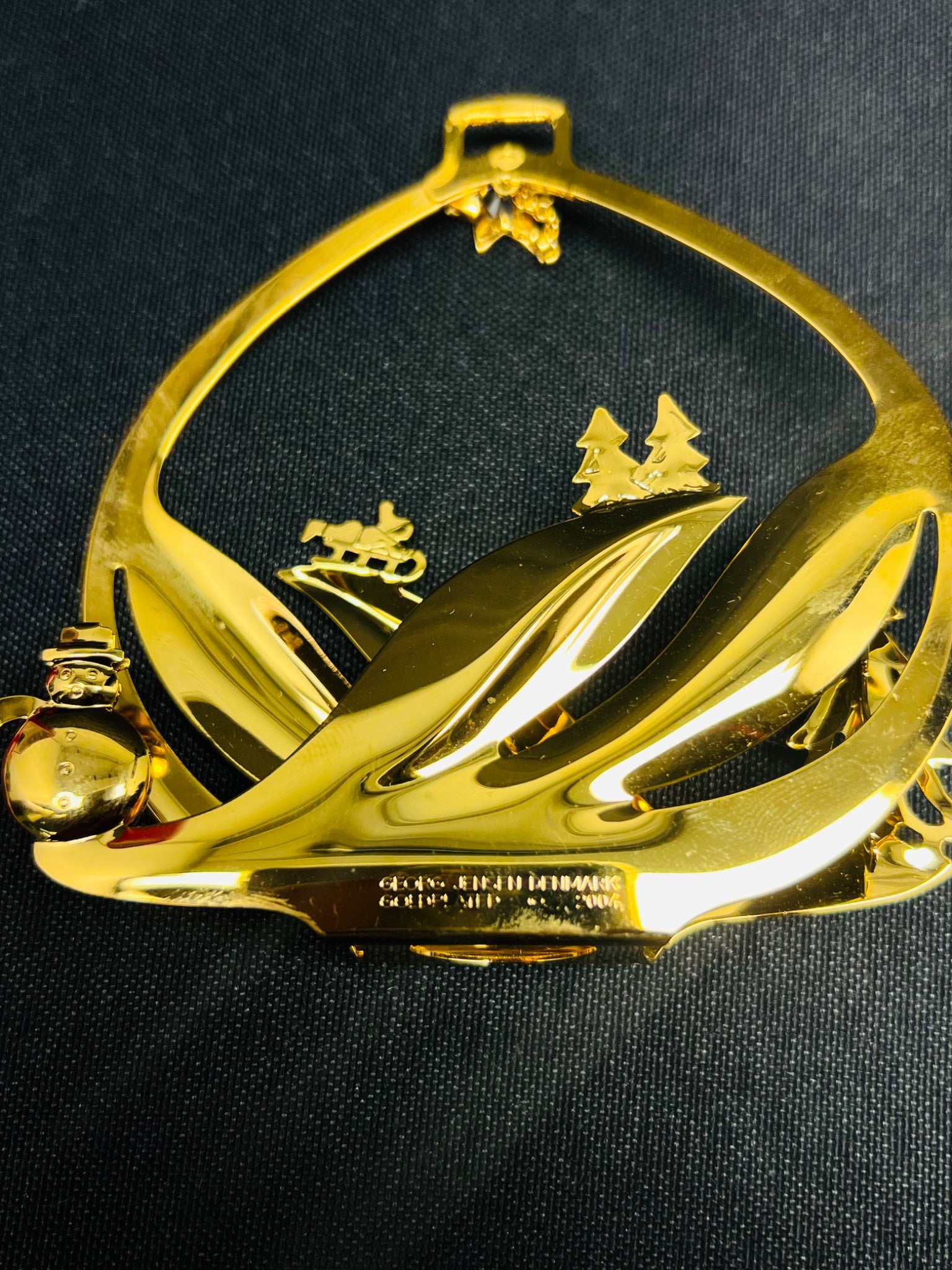 Gold decorative item with leaf design on a black background