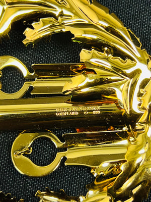 Gold-colored decorative item with intricate design on a black background