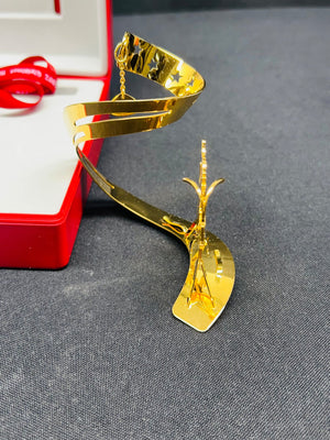 Gold spiral decorative item on a gray surface with a red box in the background