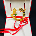 Gold ornament with red ribbon in an open red box on a black background