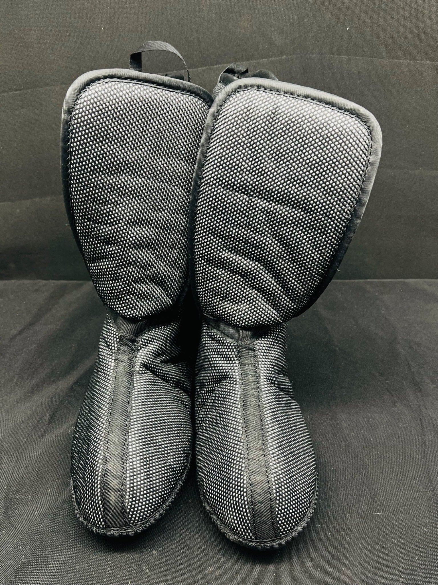 Pair of gray mesh oven mitts on a dark surface