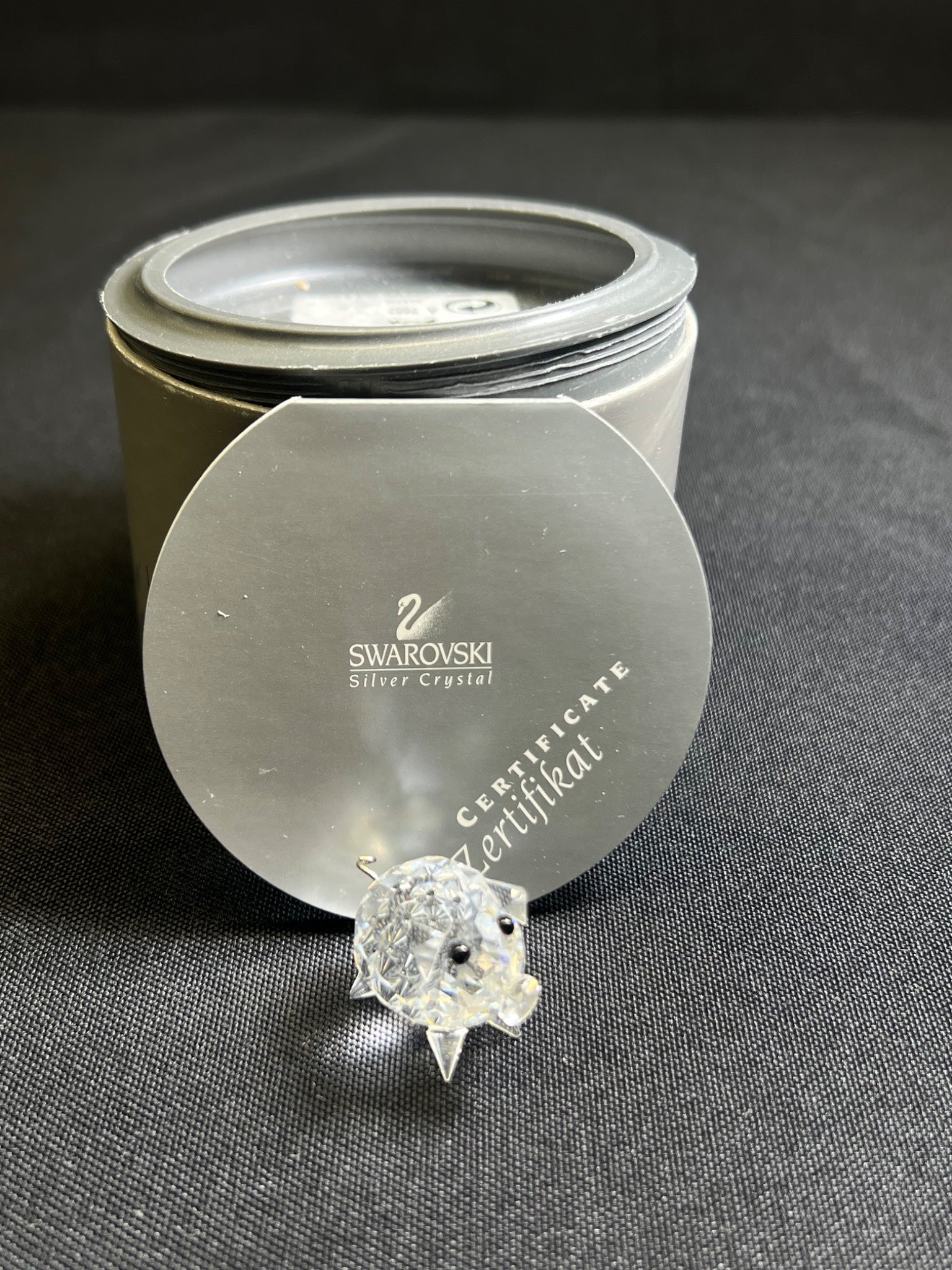 Swarovski crystal on a gray surface with a Swarovski branded container.