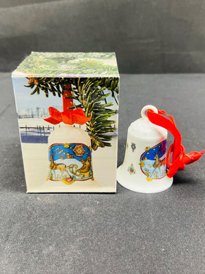 Decorative bell with red ribbon next to its packaging on a gray surface