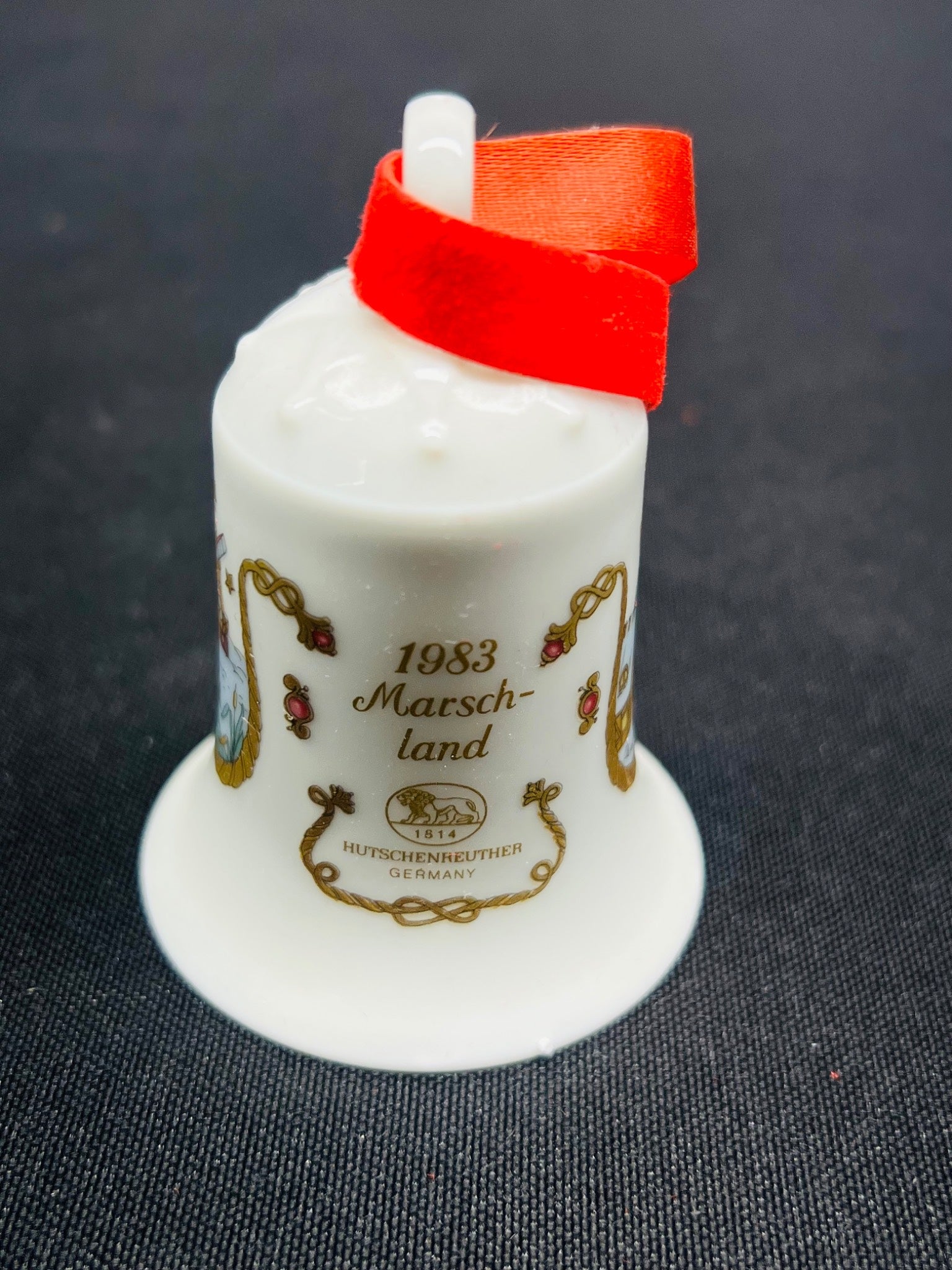 White ceramic thimble with red top on a dark textured background