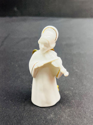 White angel figurine with gold accents on a dark fabric background