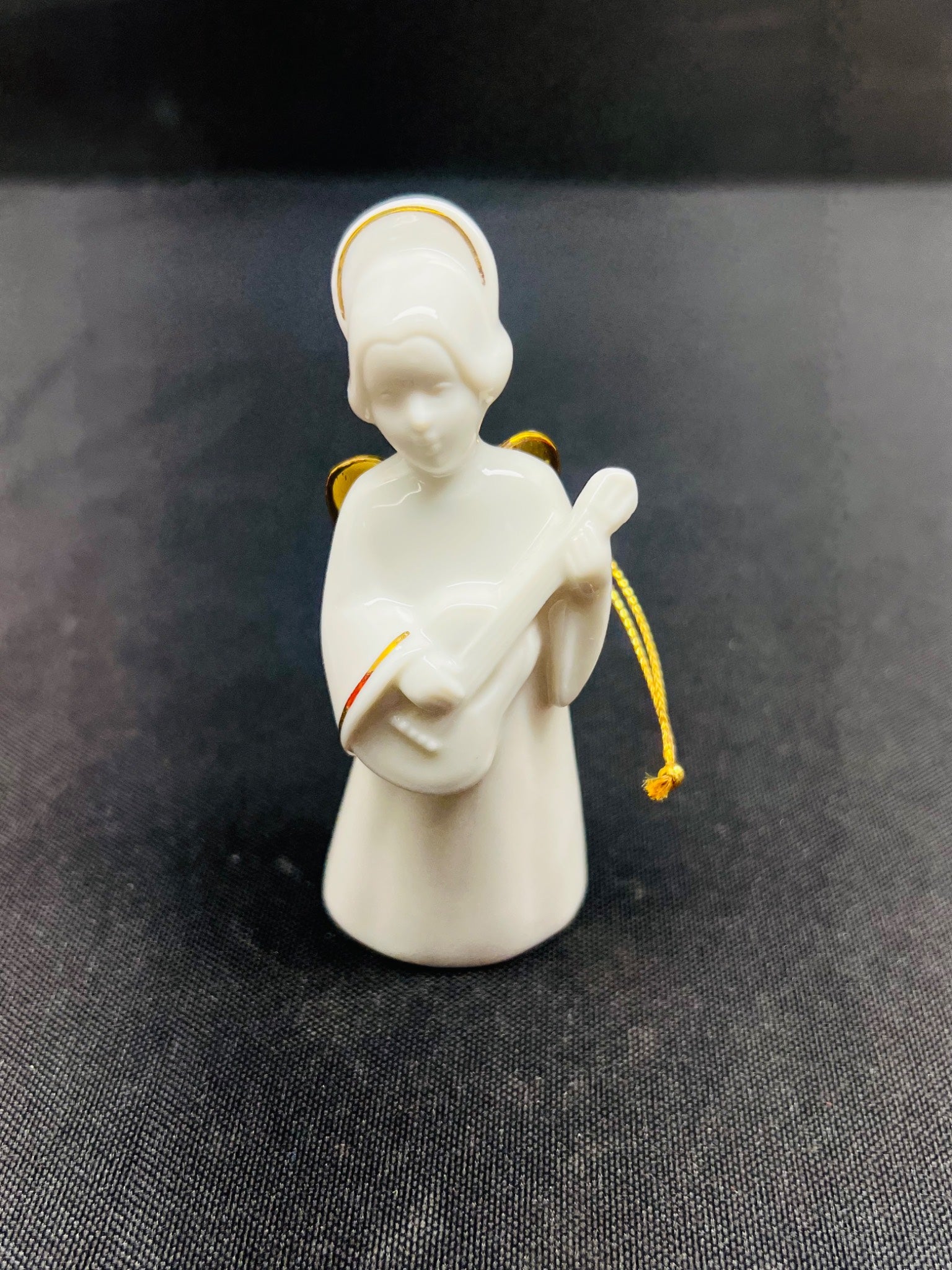 White angel figurine holding a guitar on a dark fabric background