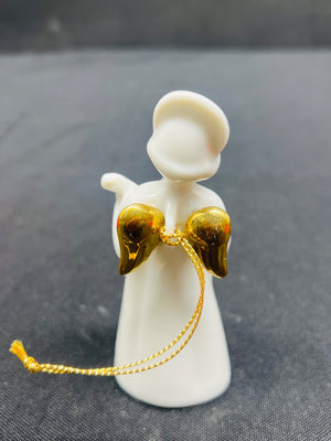 White angel figurine with gold wings and string on a dark background