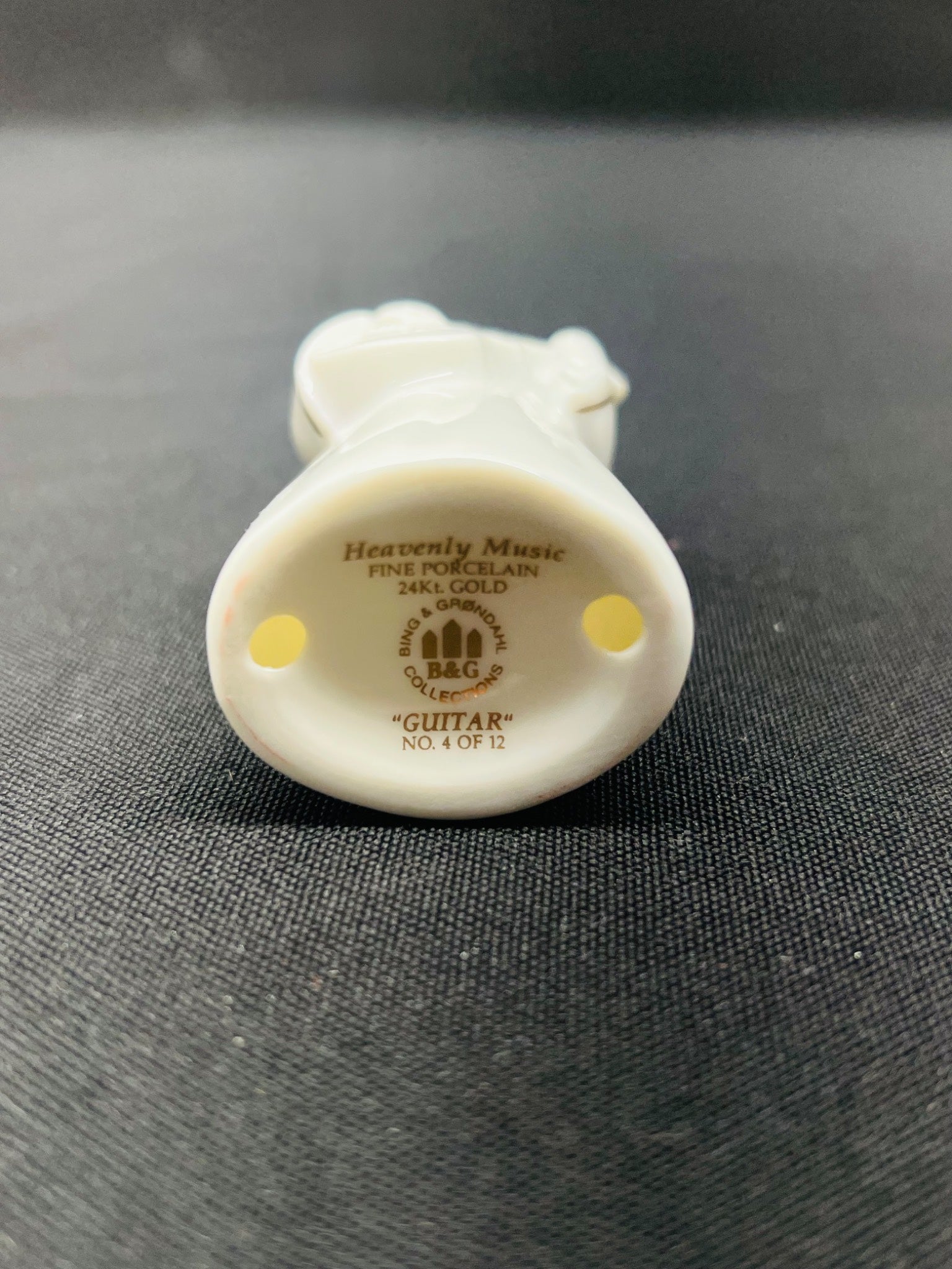 Small white figurine with 'Heavenly Music' branding on a dark textured background