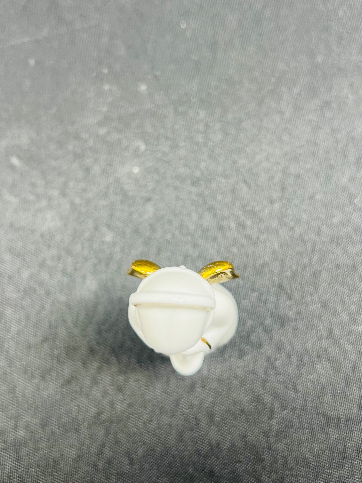 White spherical object with gold accents on a gray background