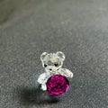 Crystal teddy bear with a pink gem on a gray fabric background