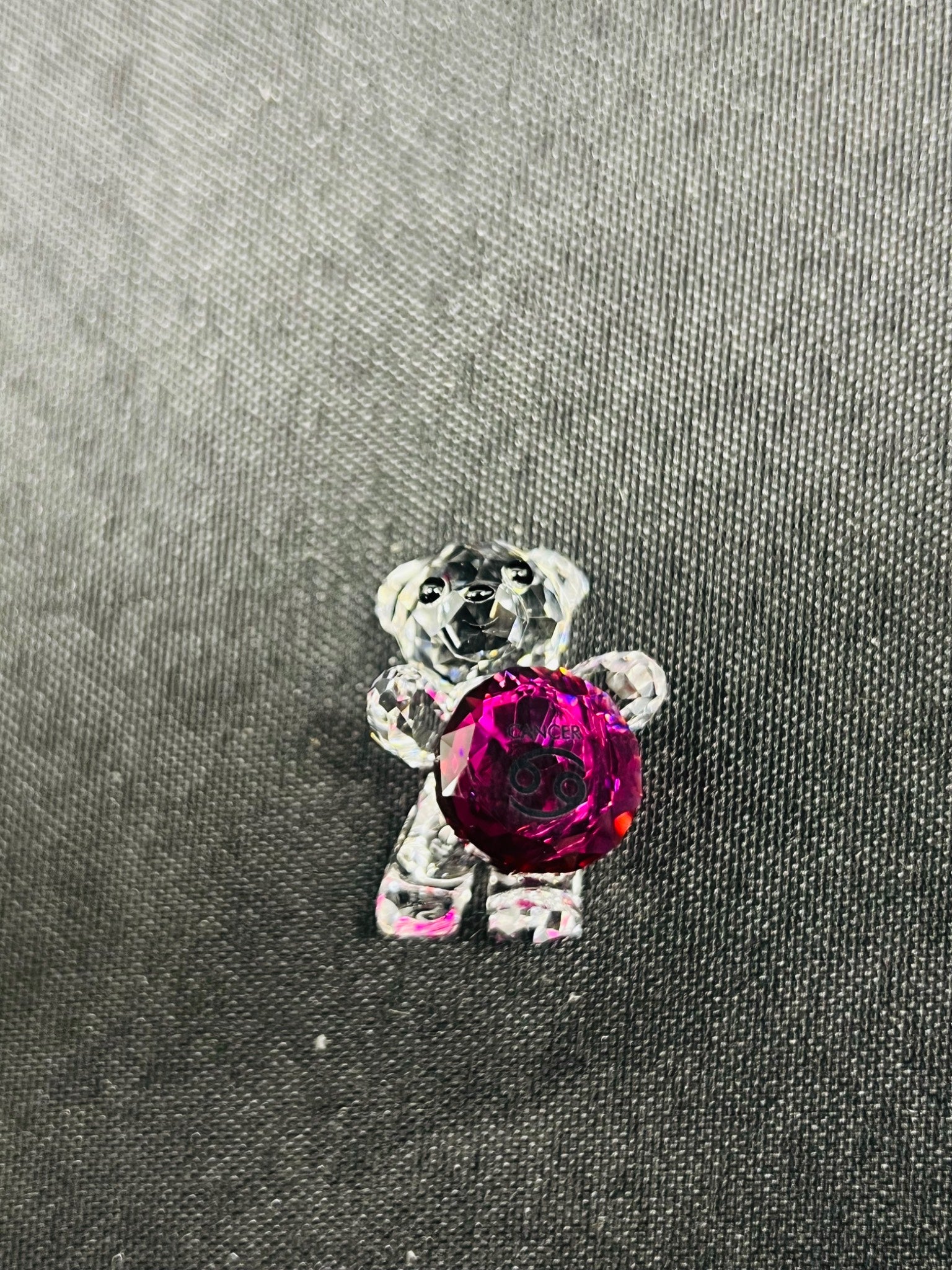 Crystal bear brooch with a red gem on a gray fabric background