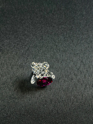 Silver ring with a purple gemstone on a dark fabric background