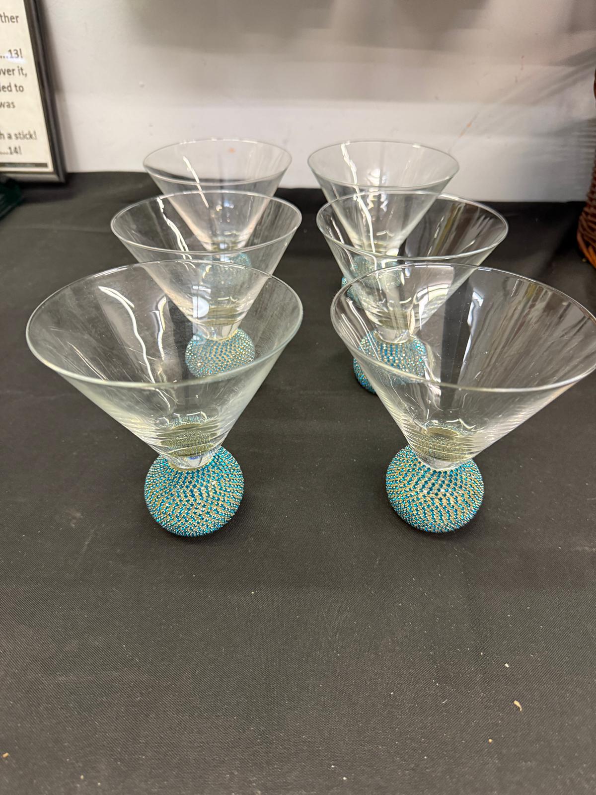 Set of five martini glasses with textured turquoise bases on a dark surface.