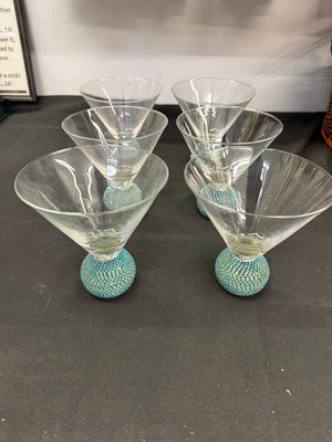 Set of five martini glasses with textured turquoise bases on a dark surface.