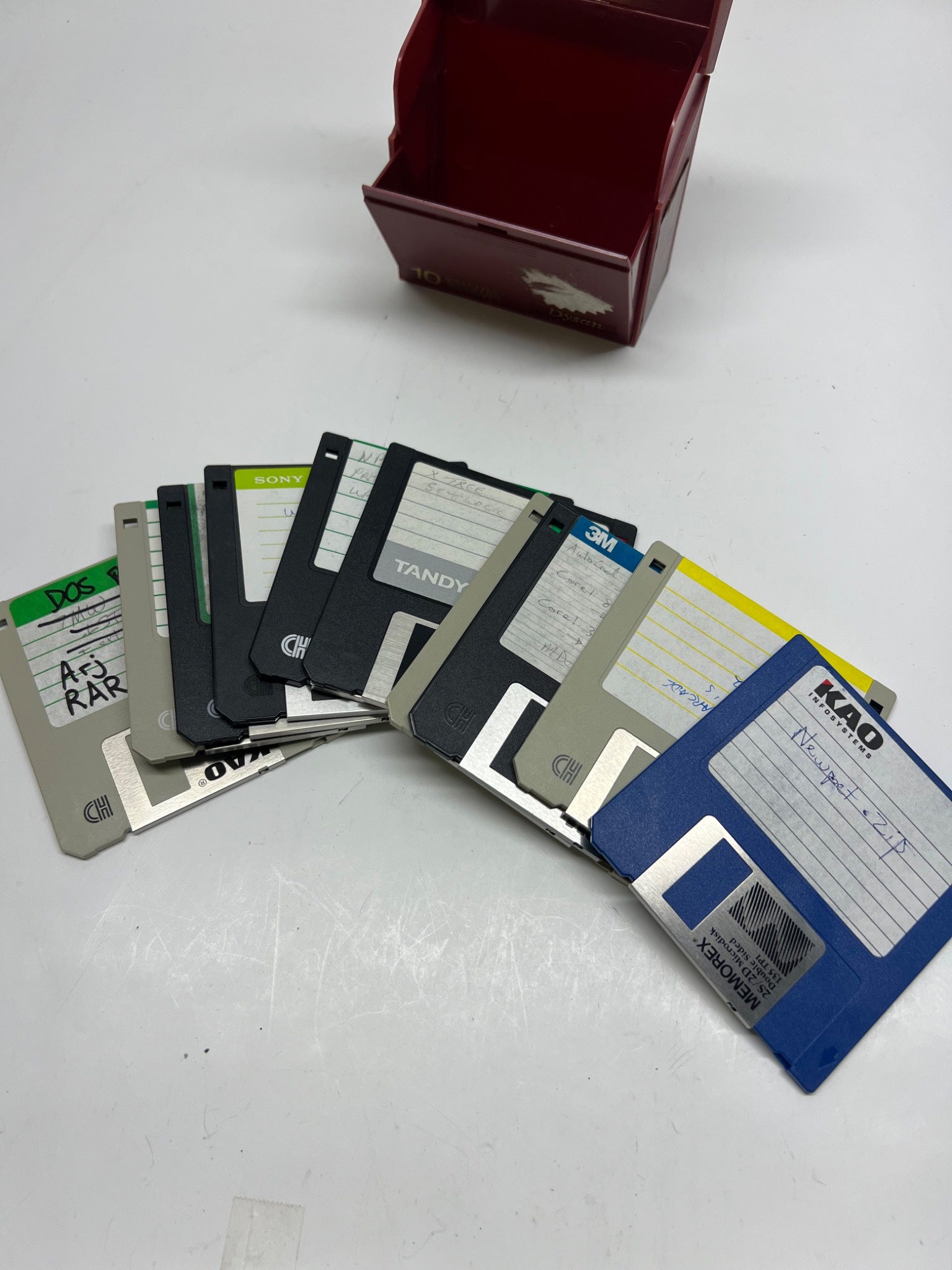 Collection of floppy disks on a white surface with a box in the background