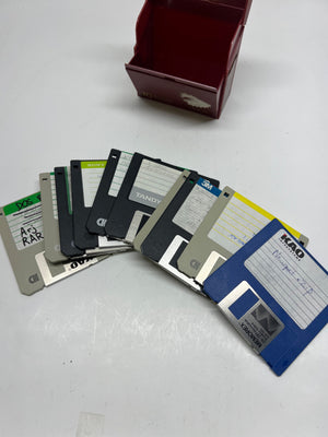 Collection of floppy disks on a white surface with a box in the background