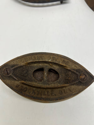 Bronze eye-shaped object with engraved text on a white background