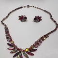 Necklace and earrings with multicolored gemstones on a light gray background